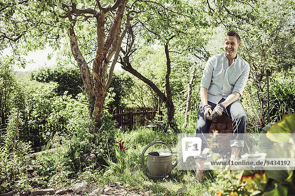 Fröhlicher junger Mann beim Gärtnern auf dem Hof