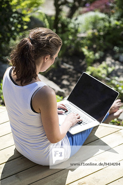 Hochwinkelansicht der mittleren erwachsenen Frau mit Laptop auf der Terrasse