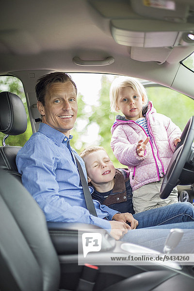 Porträt eines glücklichen Vaters mit Kindern im Auto