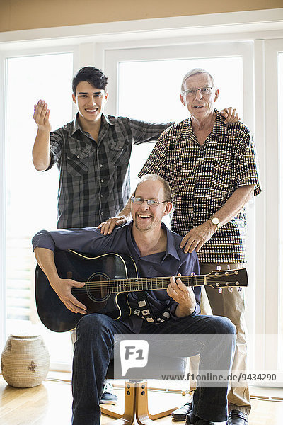 Portrait of mature man playing guitar for father and son at home