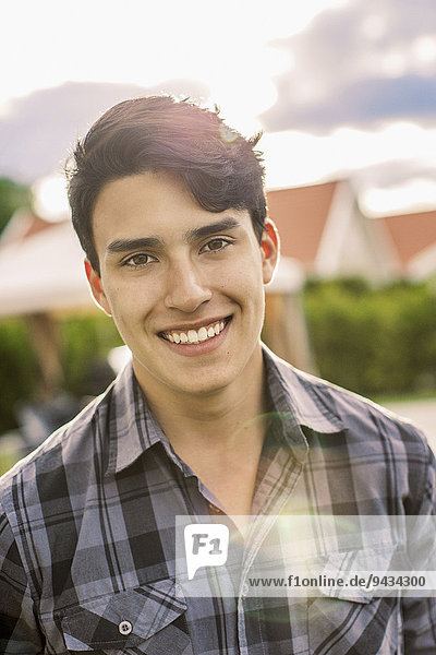 Porträt eines selbstbewussten jungen Mannes  der im Freien lächelt.