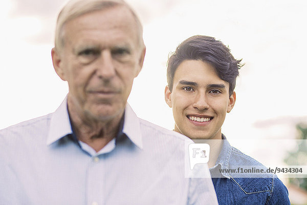 Porträt eines jungen Mannes  der mit Großvater im Vordergrund lächelt