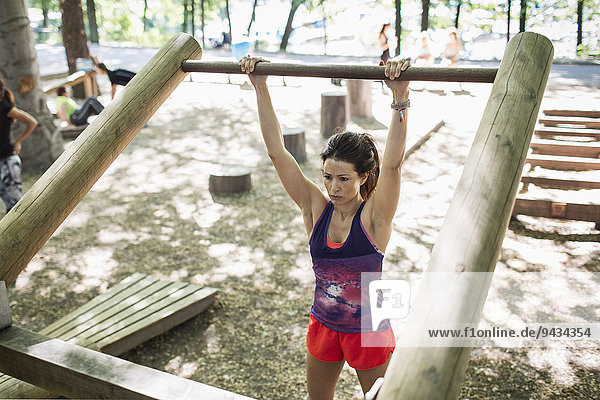 Determined woman lifting wooden bar at outdoor gym