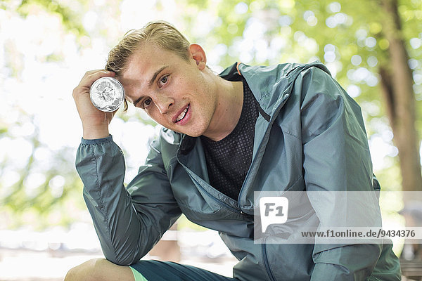 Portrait of smiling fit man holding water bottle at park