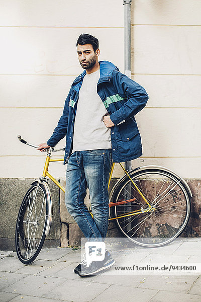 Ganzkörperporträt eines selbstbewussten Mannes mit Fahrrad auf dem Bürgersteig