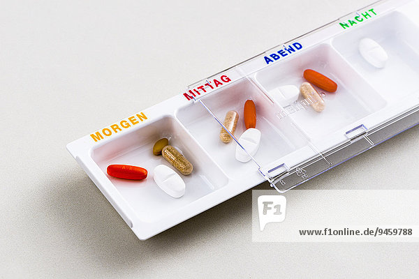Tablettenspender  gefüllt mit Pillen für den ganzen Tag  auf Deutsch beschriftet
