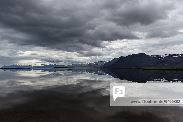 See  hinten Berge  dunkle Wolken spiegeln sich im Wasser  bei Gardar  Halbinsel Snæfellsnes  Island  Europa