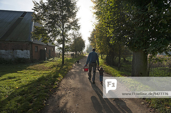 Vater mit kleiner Tochter an der Hand auf einem Weg am Morgen  Othenstorf  Mecklenburg-Vorpommern  Deutschland  Europa