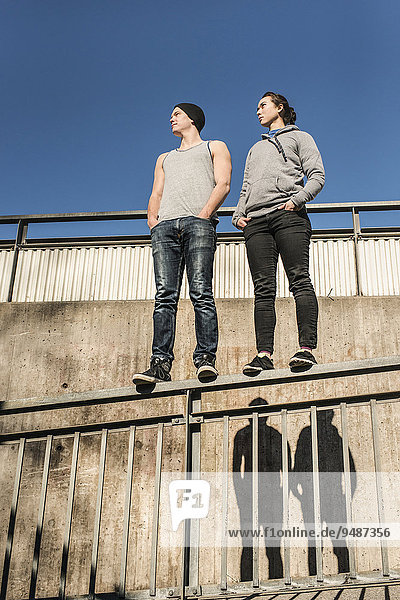 Lässig und entspannter junger Mann und eine junge Frau stehen auf einem Geländer in einem Stadtgebiet  Schweden  Europa
