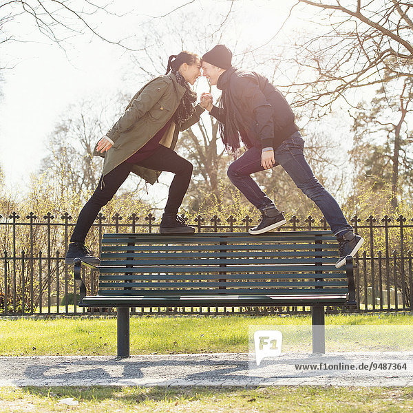 Paar in einer Beziehung  ein junges Paar steht händchenhaltend auf einer Parkbank  Schweden  Europa