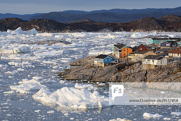 Bunte Holzhäuser am Meer mit Bruchstücken eines Eisbergs  Ilulissat  Grönland