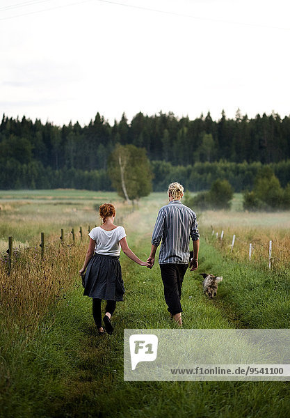 Young couple walking through grassy road