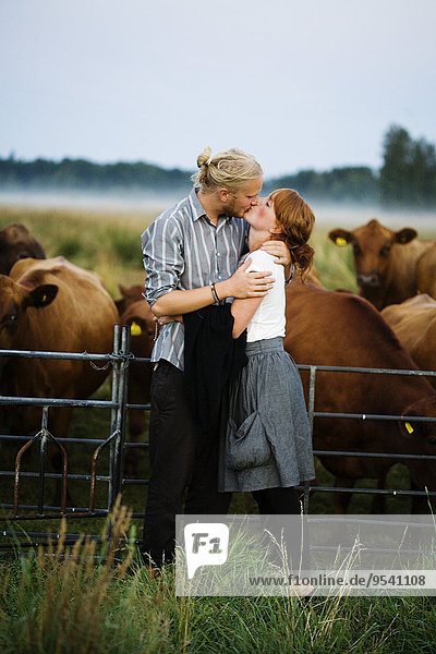 Young couple kissing  pasture on background