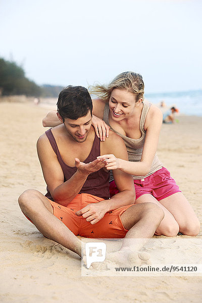 Young couple on beach looking at shells