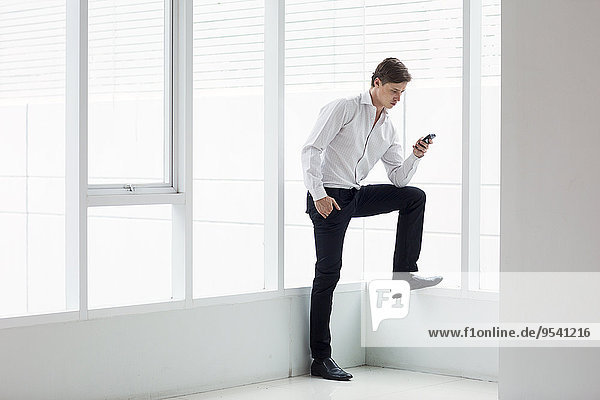 Businessman with cell phone in office building