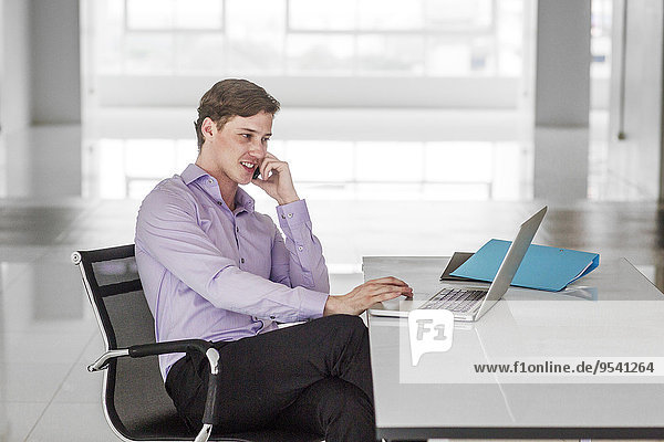 Smiling businessman on the phone in office