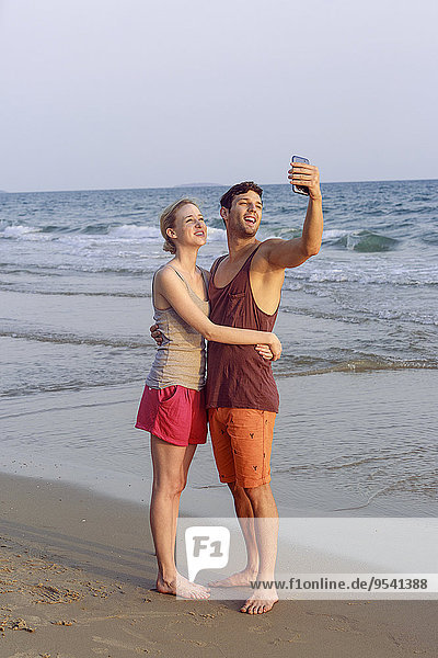 Young couple at beach taking selfie