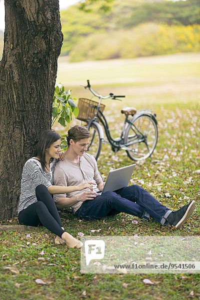 Young couple using laptop in park