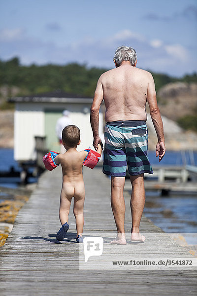 Grandfather walking with grandson on jetty