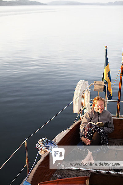 Young woman on boat with book
