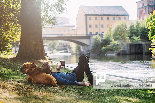 Young man lying down with his dog in park