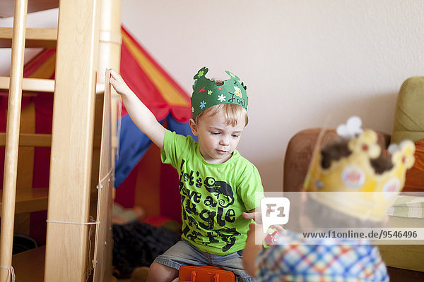 Zwei kleine Jungen mit Papierkronen beim Spielen im Kinderzimmer
