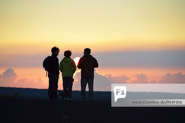USA  Hawaii  Big Island  Volcanoes National Park  three persons watching sunset at Kilauea Iki