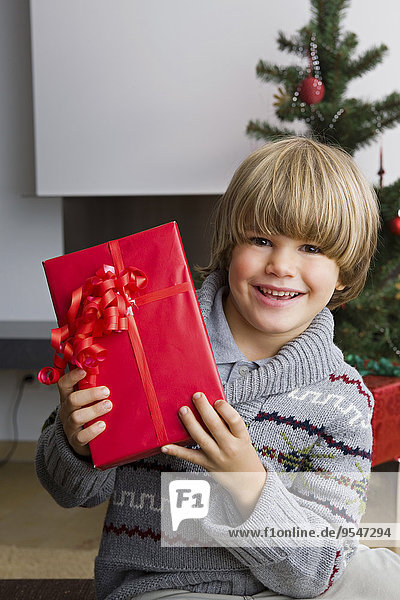 Porträt eines glücklichen kleinen Jungen mit Weihnachtsgeschenk