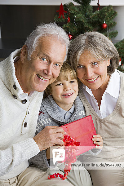 Glücklicher kleiner Junge erhält Weihnachtsgeschenk von seinen Großeltern