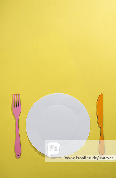 Food-Konzept mit Papier  Teller  Gabel und Messer auf gelbem Hintergrund