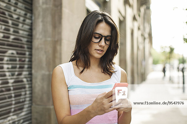 Young woman with smartphone reading SMS