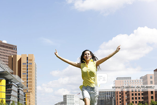 Deutschland  Berlin  glückliche junge Frau auf einer Wiese in der Nähe des Potsdamer Platzes