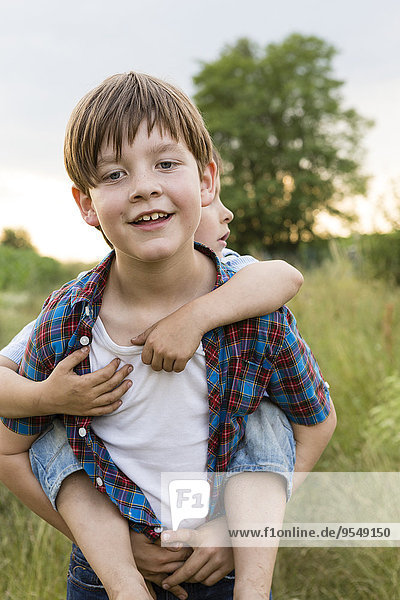 Portrait of smiling little boy giving his brother piggy back