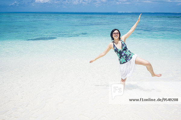 Malediven,  Ari Atoll,  junge Frau auf einem Bein im Wasser stehend