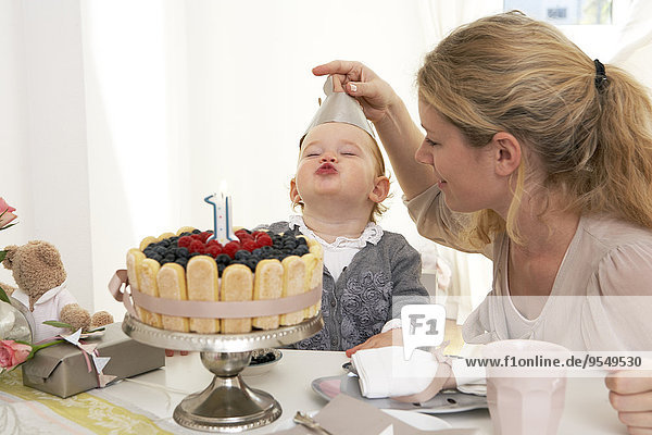 Mutter und Tochter feiern den ersten Geburtstag des kleinen Mädchens mit einem selbstgebackenen Kuchen.