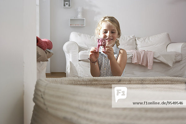 Girl at home playing with pig figurine