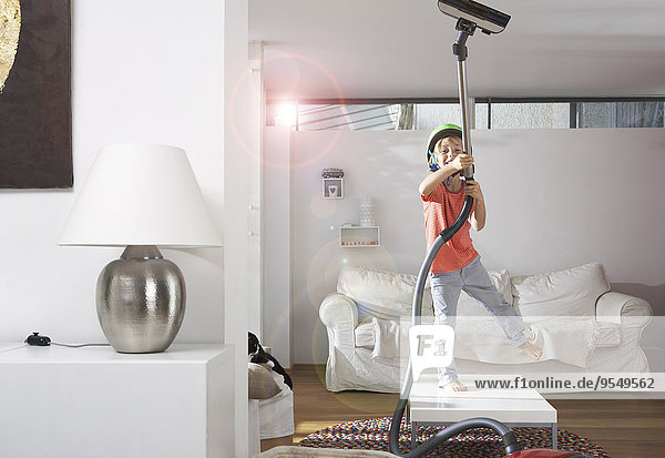 Boy in living room hoovering the ceiling