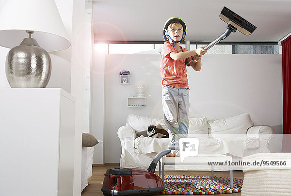Boy in living room tangled in vacuum cleaner