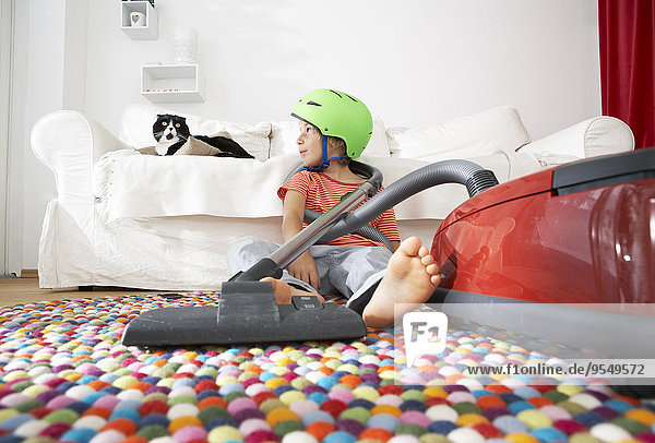 Boy in living room with cat and vacuum cleaner