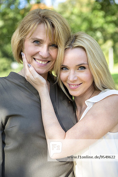 Portrait of smiling mother and adult daughter in park
