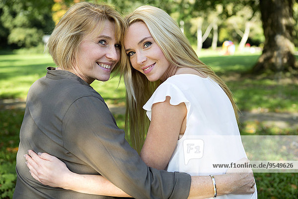 Mutter und erwachsene Tochter umarmend im Park