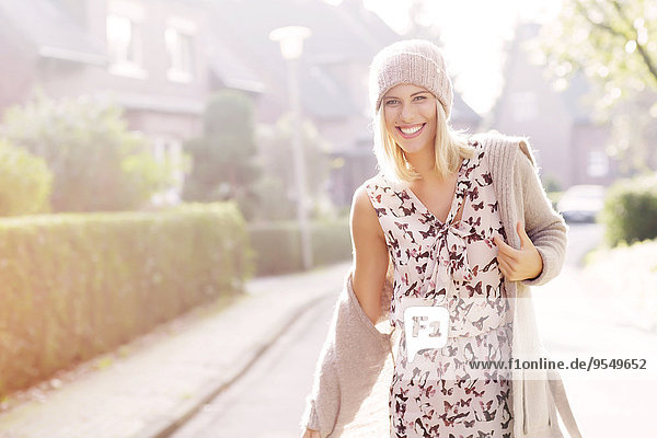 Portrait of smiling blond woman wearing patterned dress  cardigan and wool cap