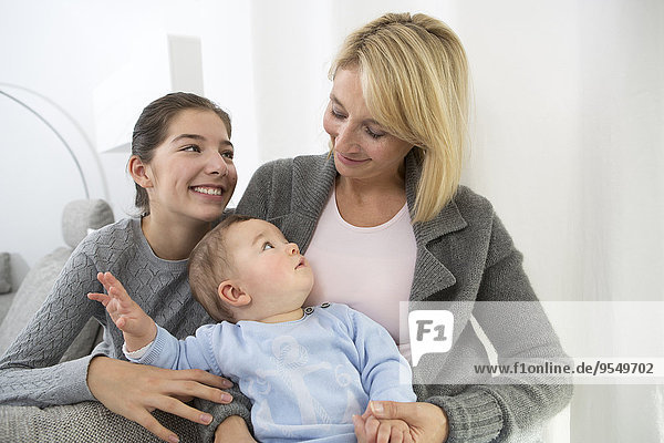 Mother sitting with daughter and baby boy on couch  smiling