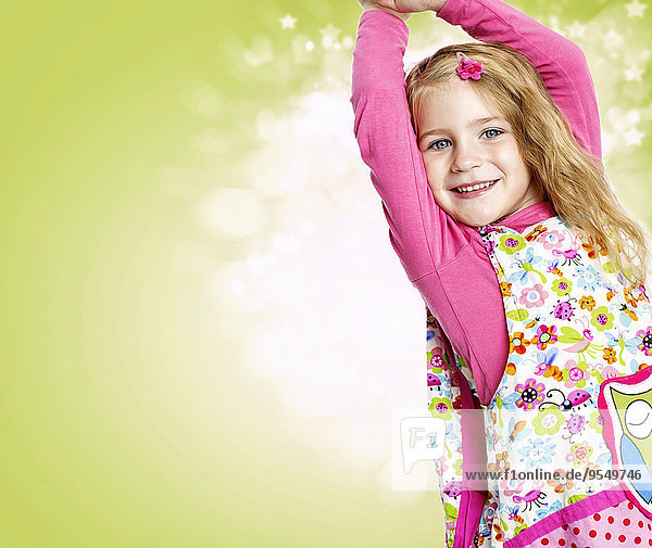 Porträt eines lächelnden Mädchens mit ausgestreckten Armen vor hellgrünem Hintergrund