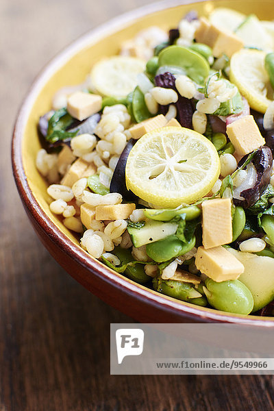 Warmer Salat mit Ackerbohnen  Schalotten  Zucchini  schwarzen Oliven  Minze  Gerste und veganem Käse