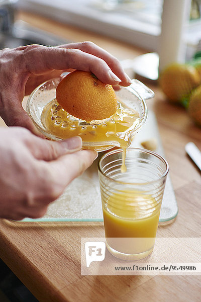 Mann gießt frisch gepressten Orangensaft in ein Glas