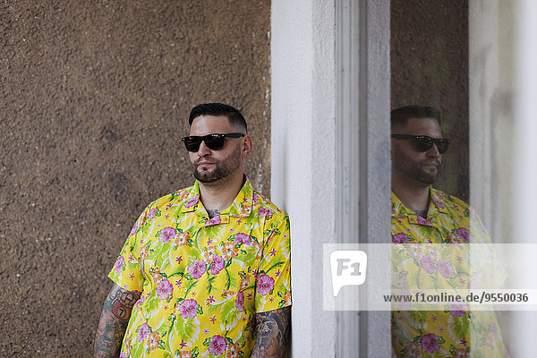 Man with fullbeard and tattoos wearing shirt with floral design and sunglasses