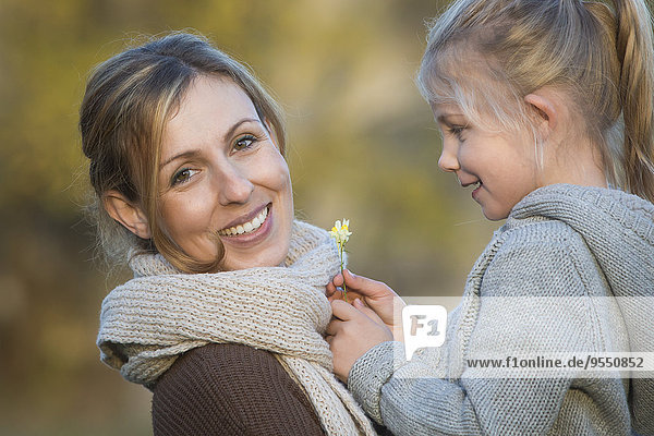Glückliche Mutter und Tochter mit Gänseblümchen im Freien