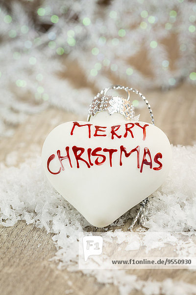 Weiße herzförmige Weihnachtskugel mit Schriftzug'Merry Christmas'.