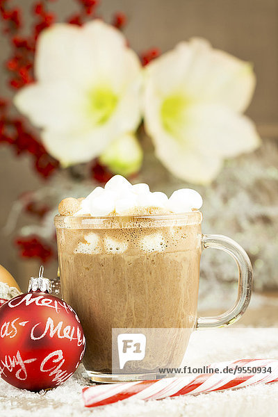 Weihnachtskugel  Zuckerrohr und Glas heiße Schokolade mit Sahne und Marshmallows auf Kunstschnee